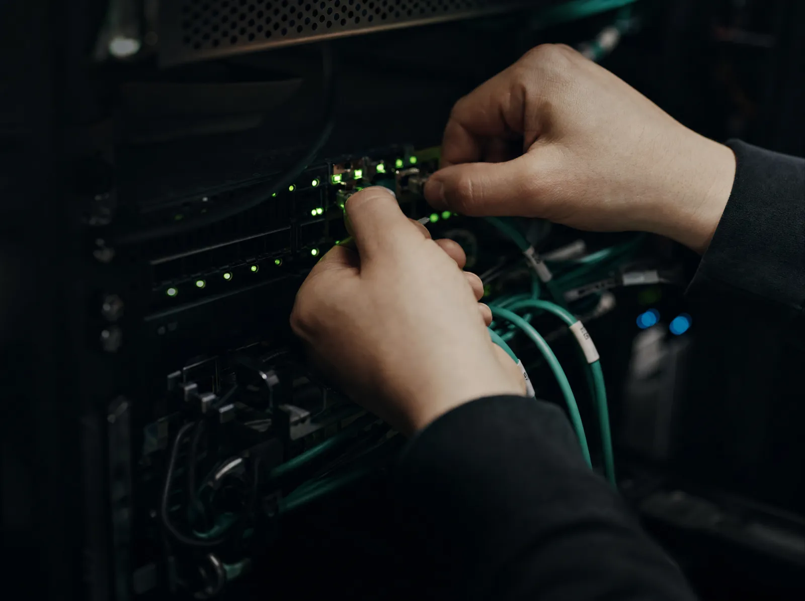 Hands patching cables in a server rack