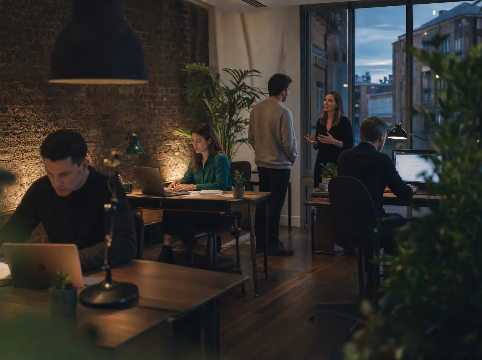 A small London office team working in the evening, brick wall behind them